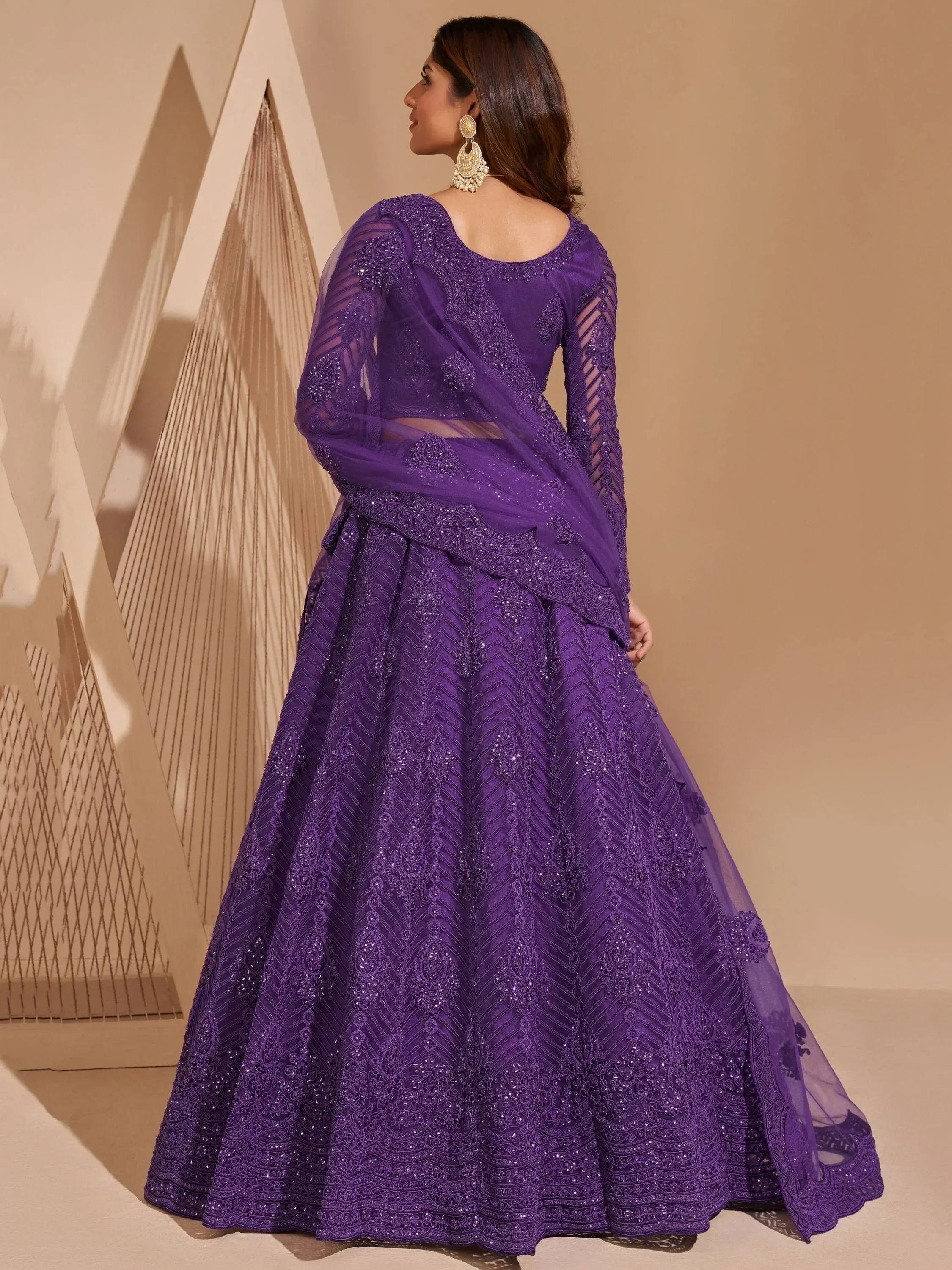 Purple designer lehenga choli with intricate embroidery and sheer sleeves, perfect for Indian ethnic occasions.