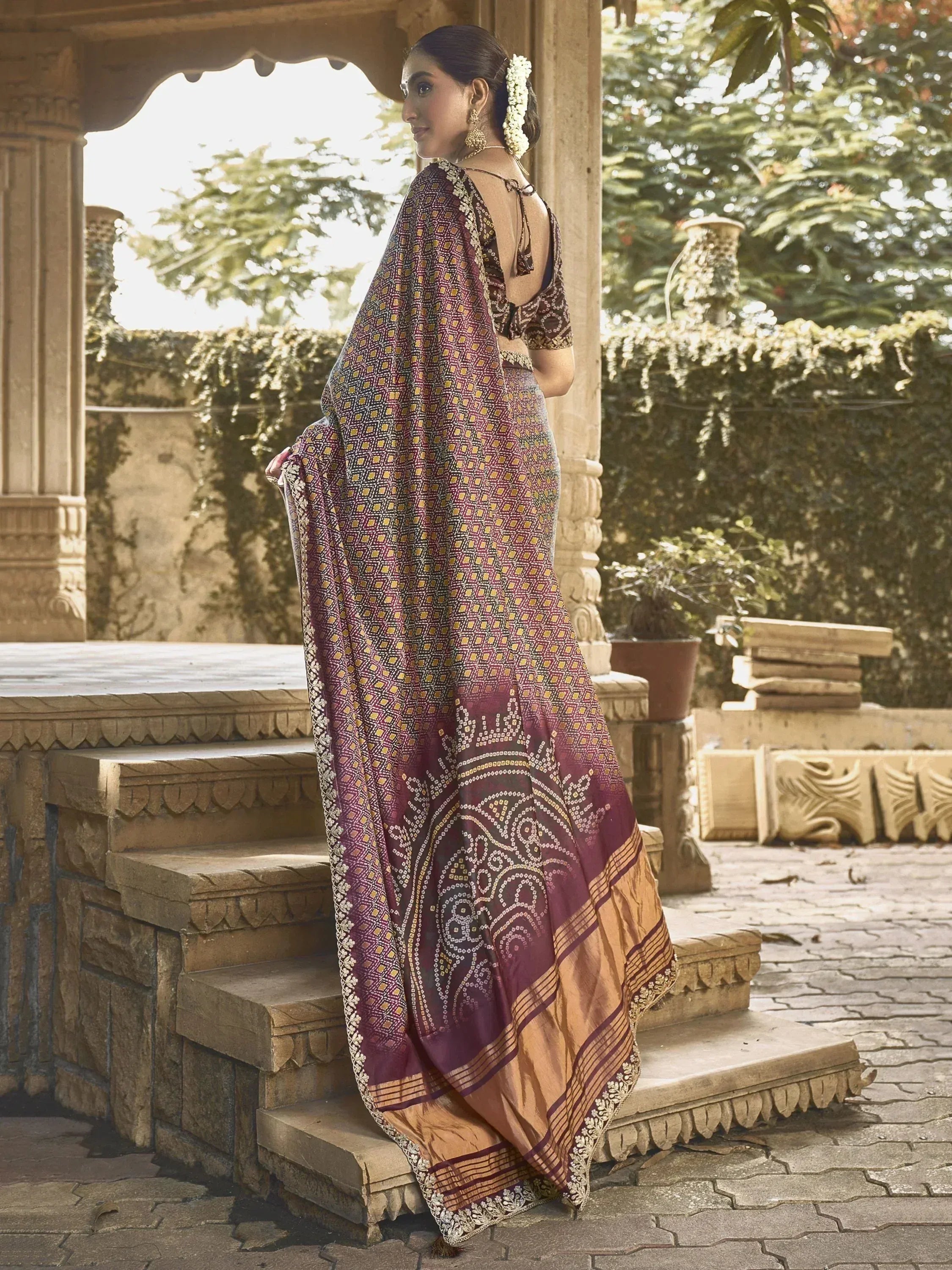 Woman in maroon and gold printed saree with backless blouse, traditional Indian ethnic wear