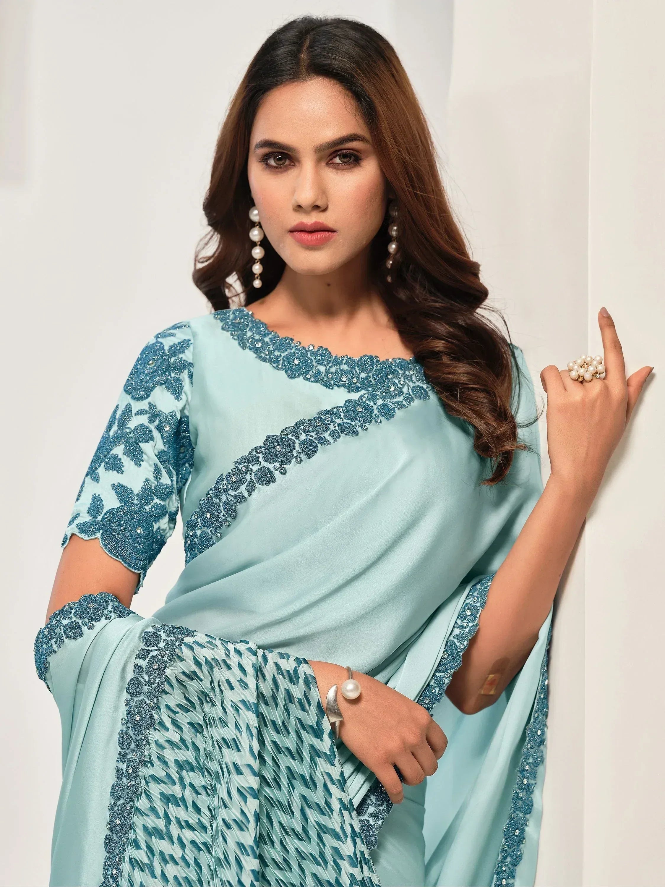 Elegant light blue saree with floral embroidery and pearl jewelry, perfect for Indian ethnic occasions