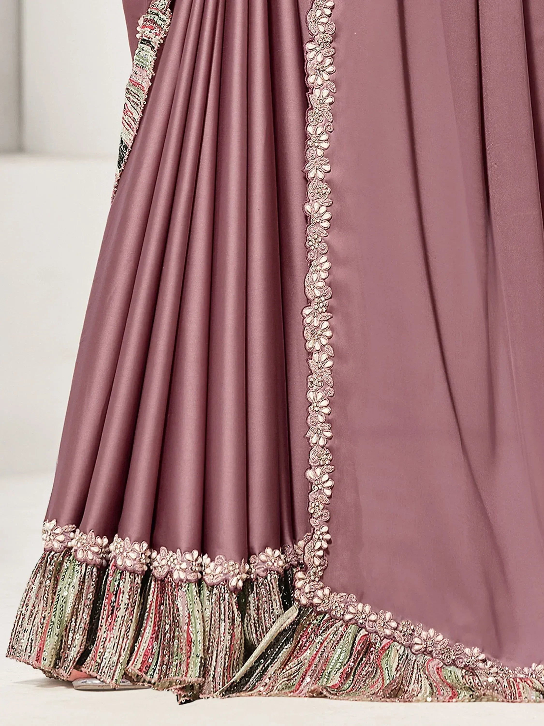 Dusty rose designer lehenga with intricate floral embroidery and colorful tassel border, perfect for Indian weddings.