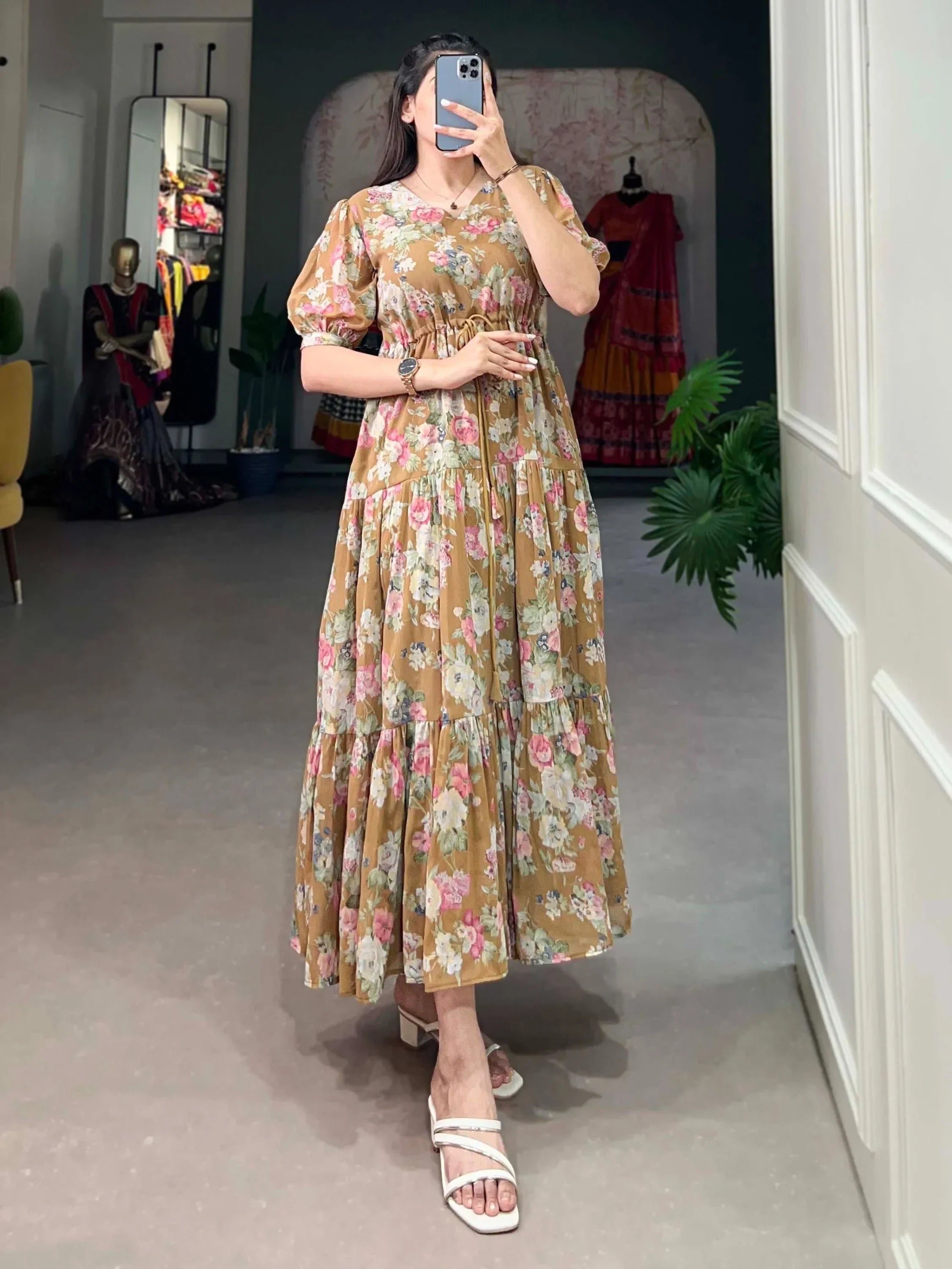 Woman wearing a brown floral printed maxi dress with puff sleeves, posing indoors.