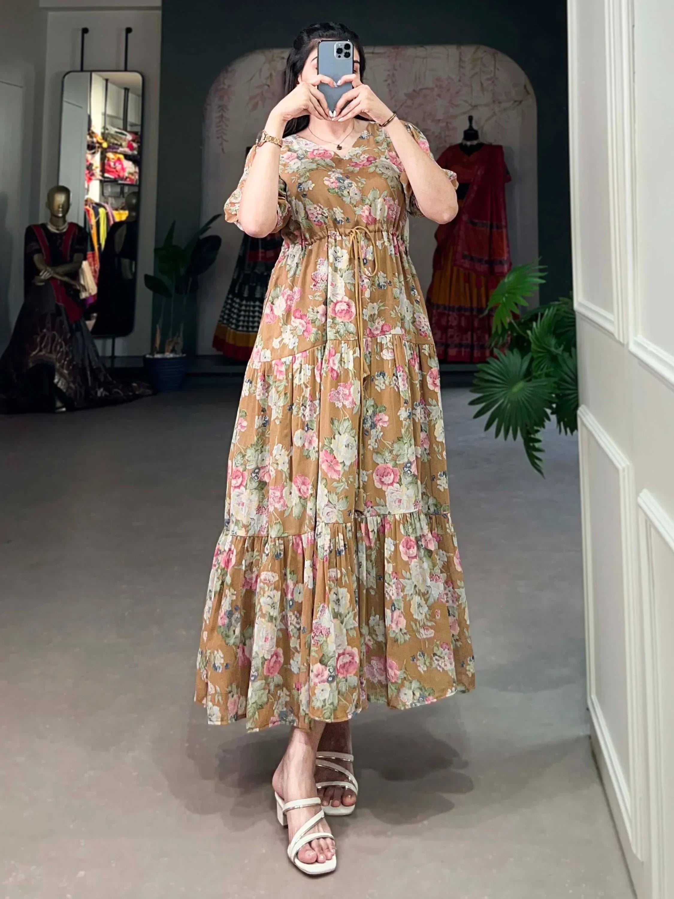 Woman in brown floral maxi dress with short sleeves, posing indoors, ethnic wear shop background