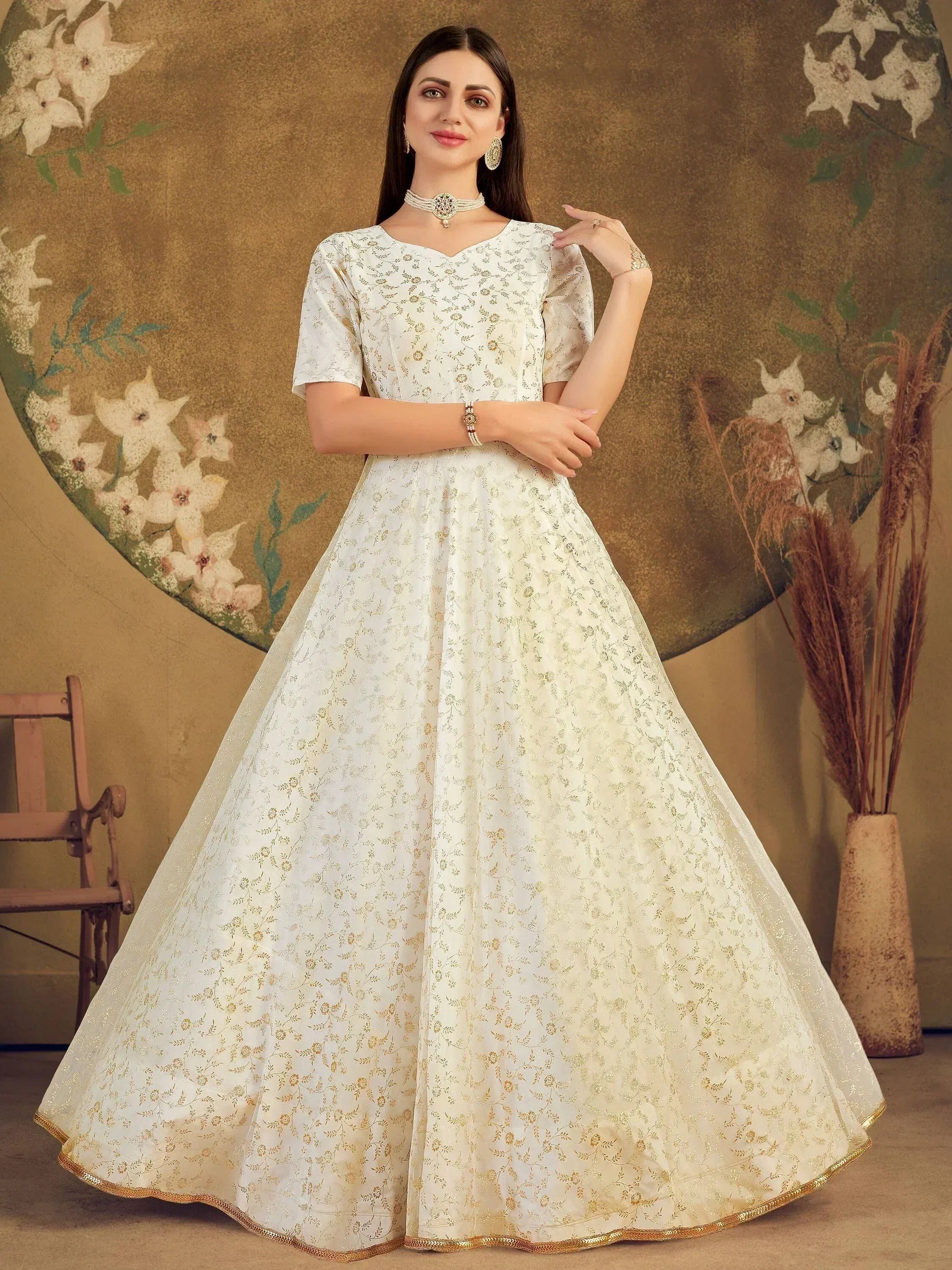 Elegant white ethnic gown with gold floral embroidery, perfect for Indian weddings and festive occasions.