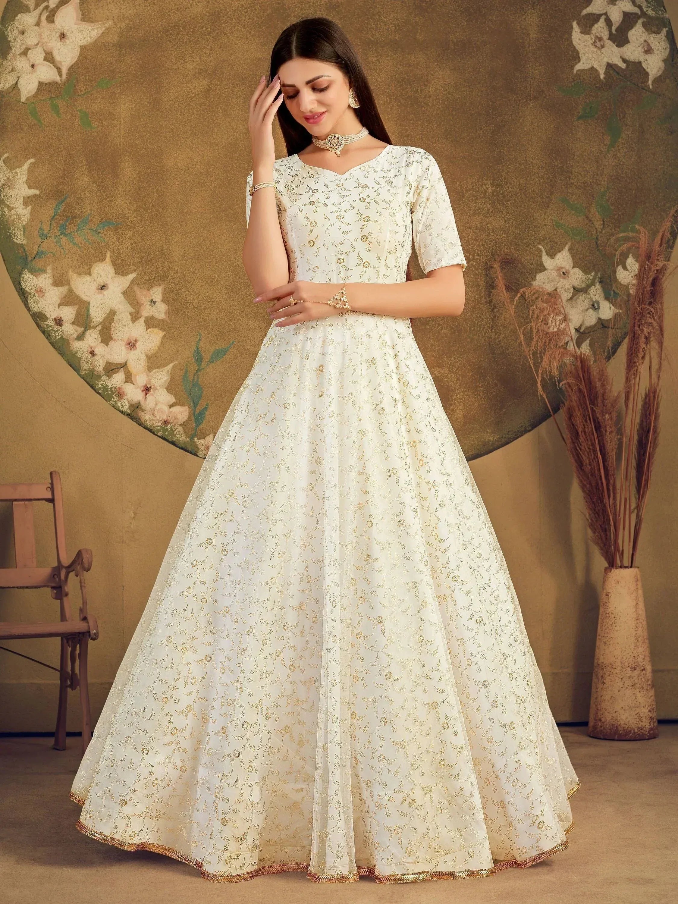 Elegant white ethnic gown with gold floral embroidery, perfect for Indian weddings and festive occasions.