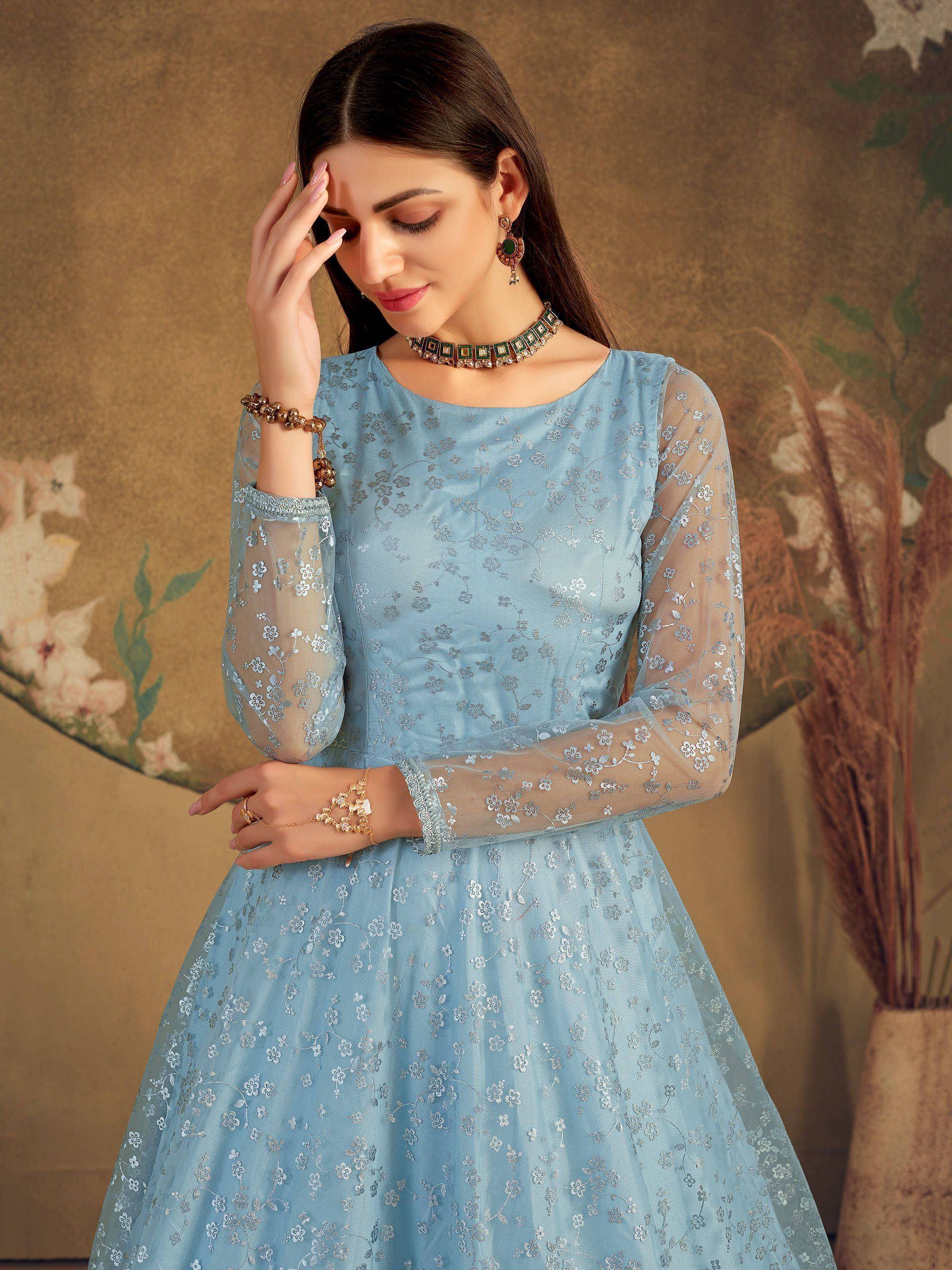 Woman in light blue floral embroidered ethnic gown with sheer sleeves and statement jewelry