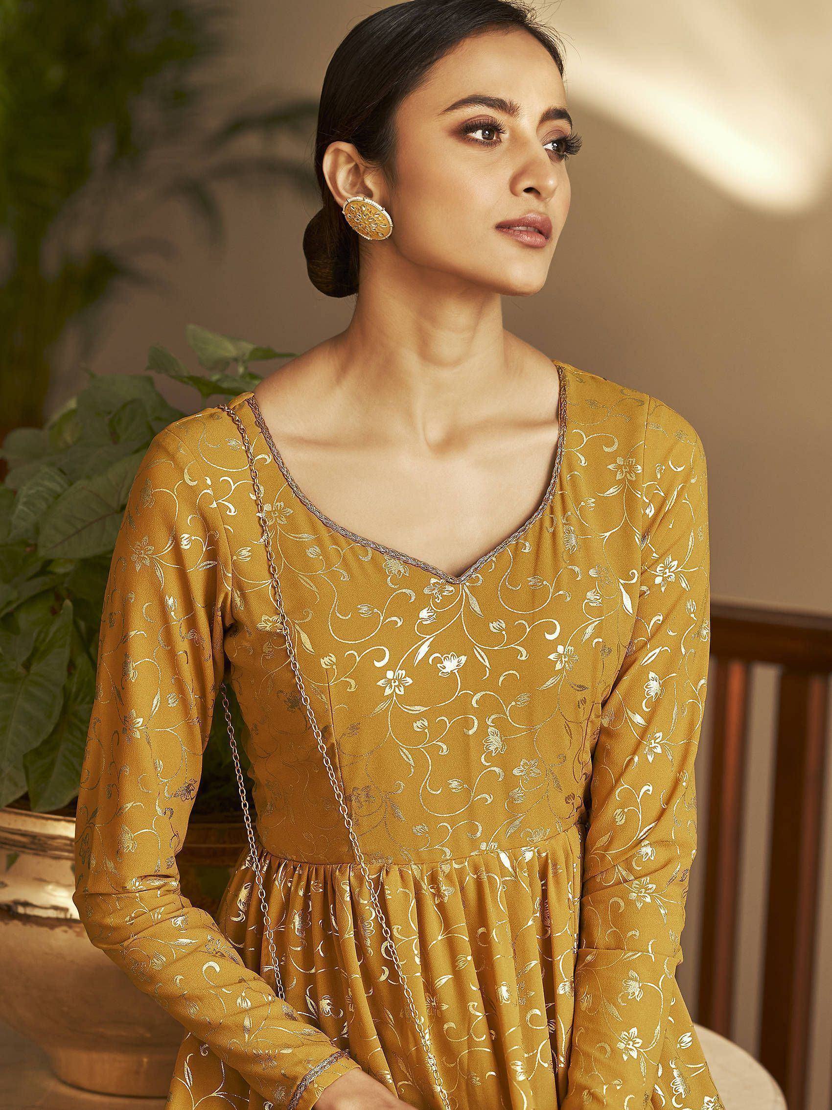 Woman wearing mustard yellow ethnic gown with silver floral embroidery and statement earrings