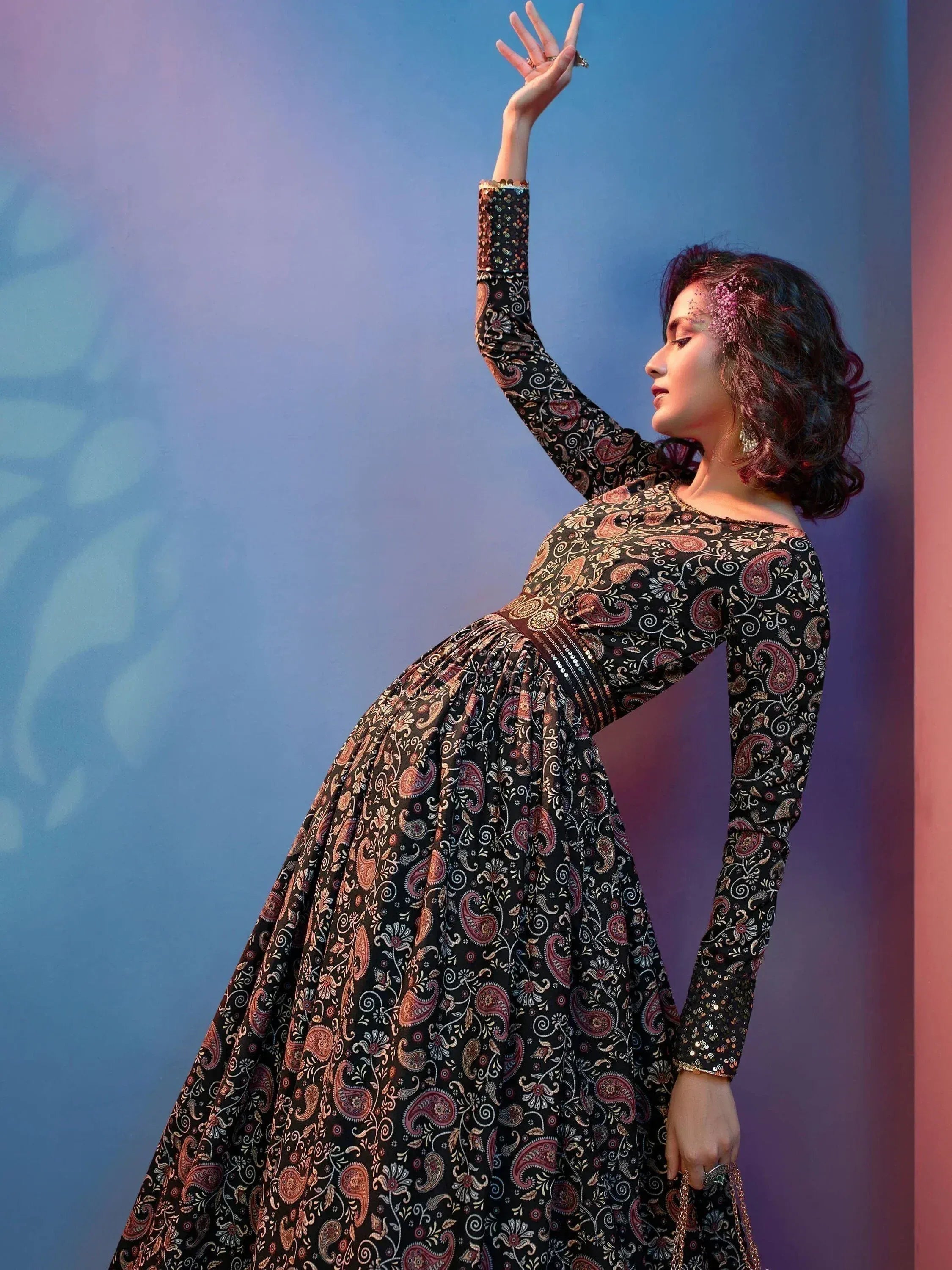 Woman in black paisley print ethnic gown with sequin sleeves, perfect for Indian occasions.