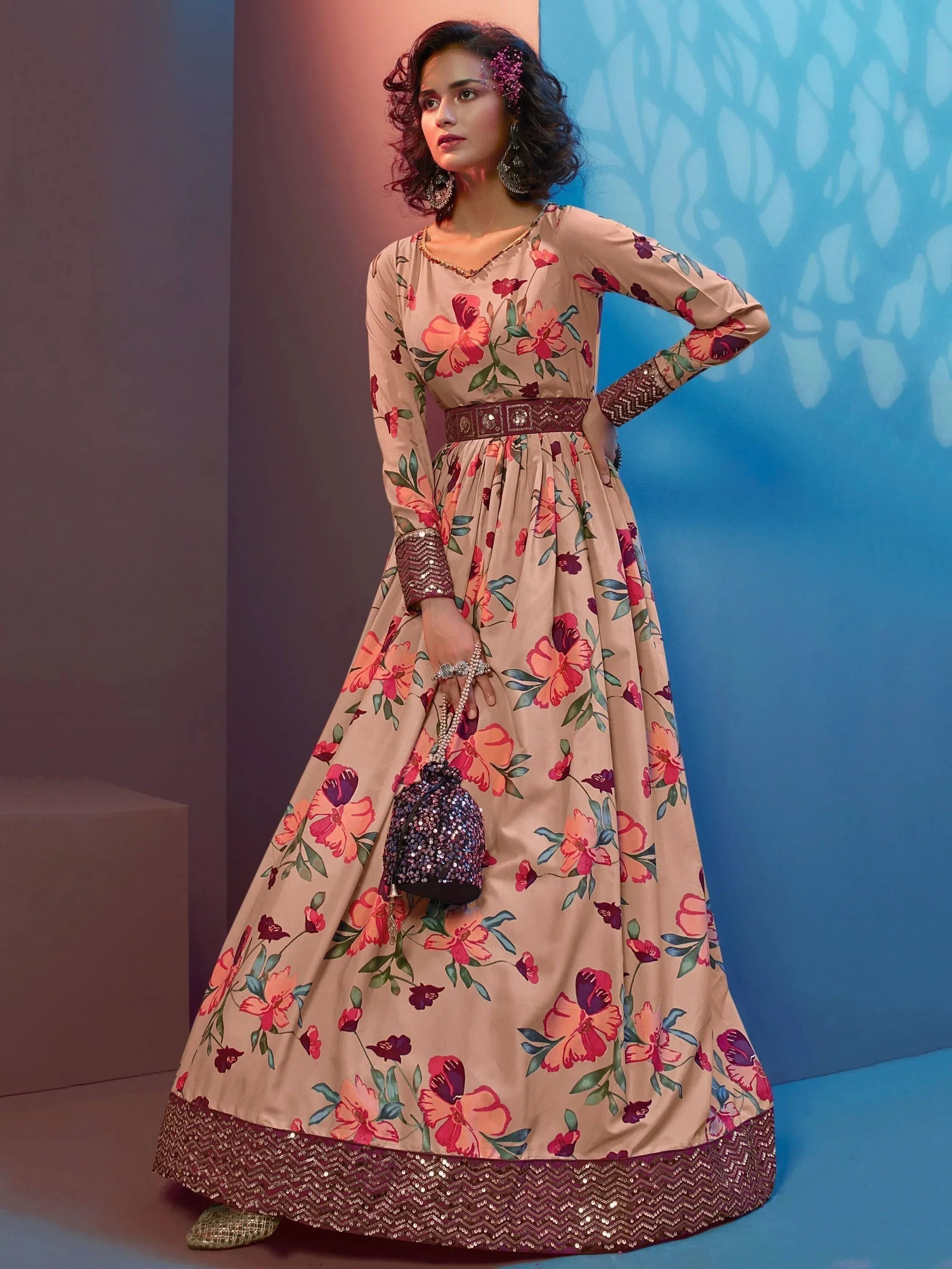 Woman wearing floral print ethnic gown with sequins border and holding embellished potli bag