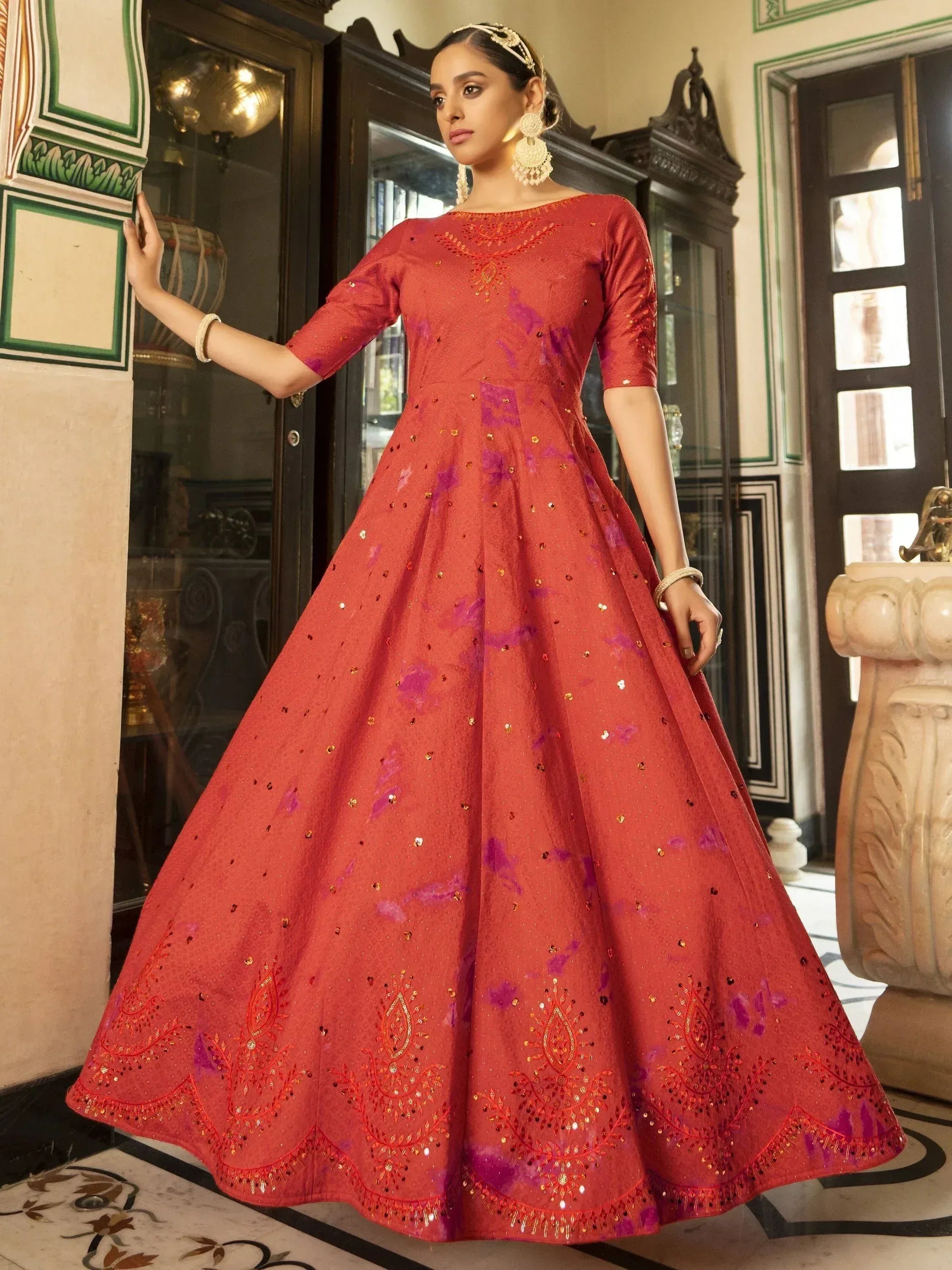 Red ethnic gown with purple floral print and gold embroidery, perfect for Indian weddings or festive occasions.