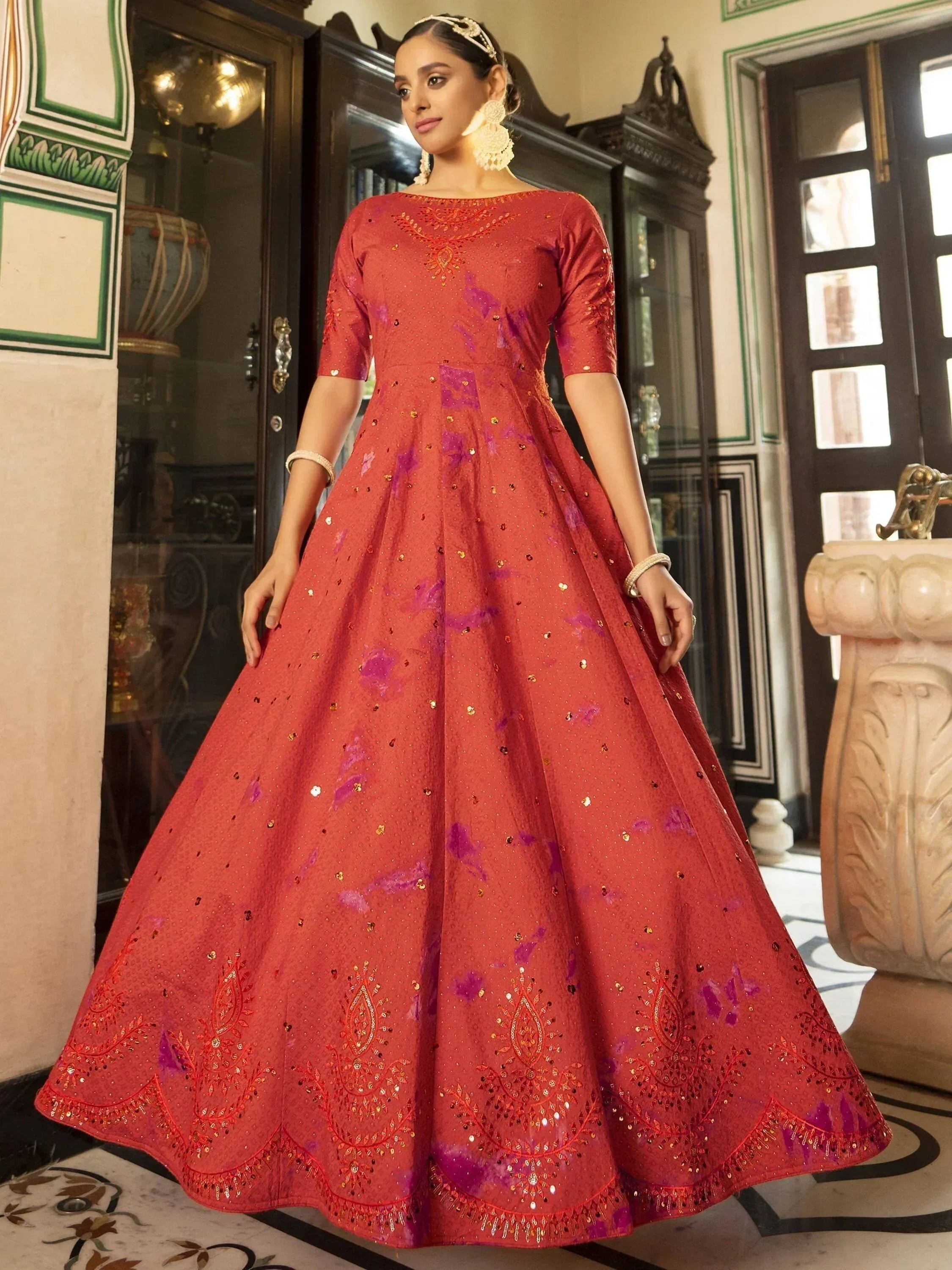 Red ethnic gown with purple floral print and gold embroidery, perfect for Indian weddings and festive occasions.