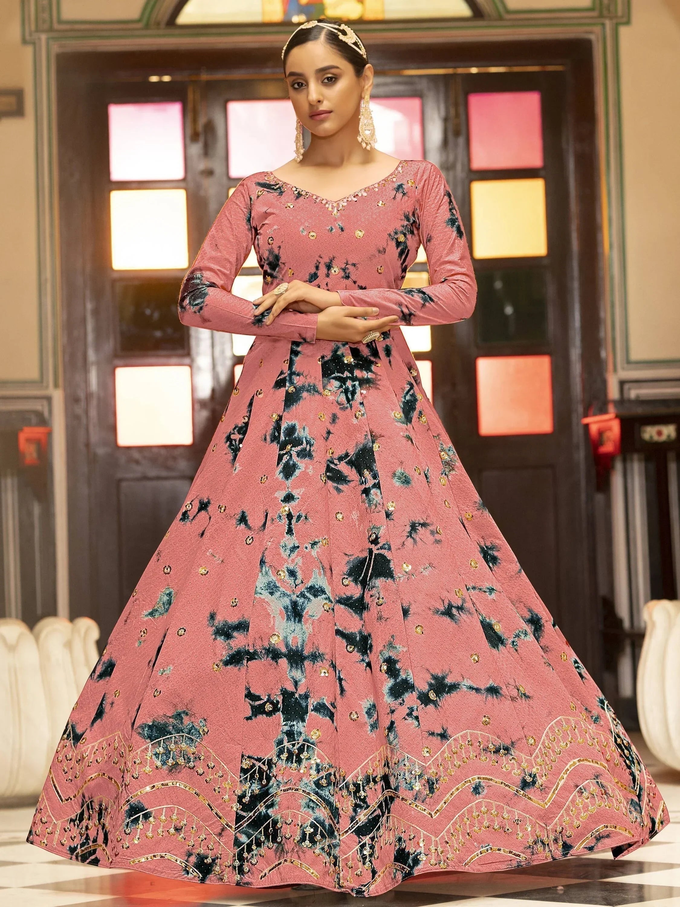 Woman in pink floral embroidered ethnic gown with long sleeves, standing indoors