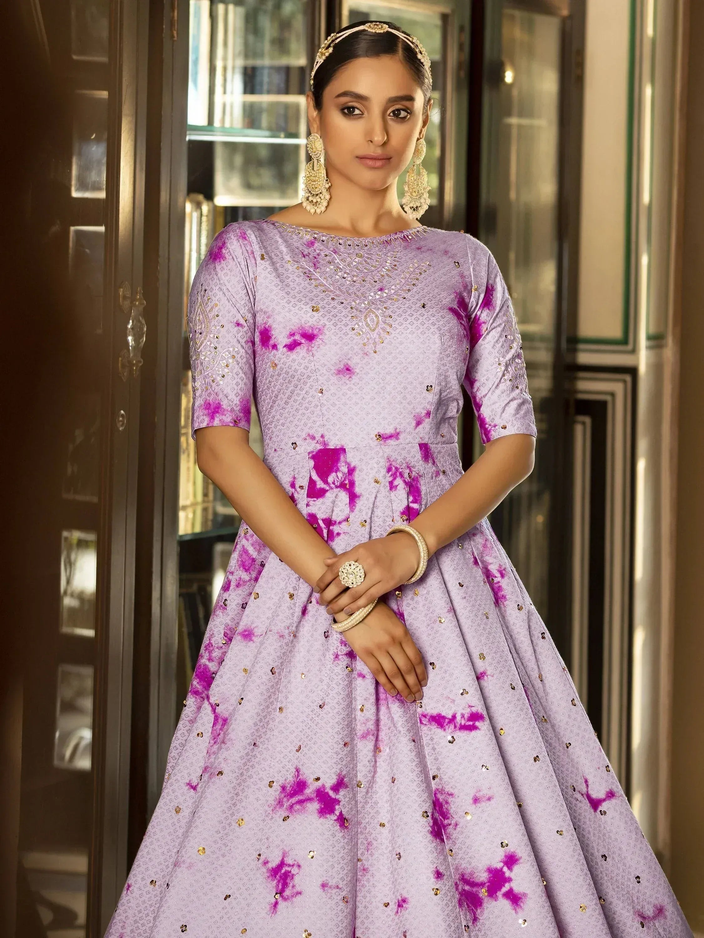 Lavender ethnic gown with pink tie-dye print and gold embroidery, perfect for Indian weddings or parties.