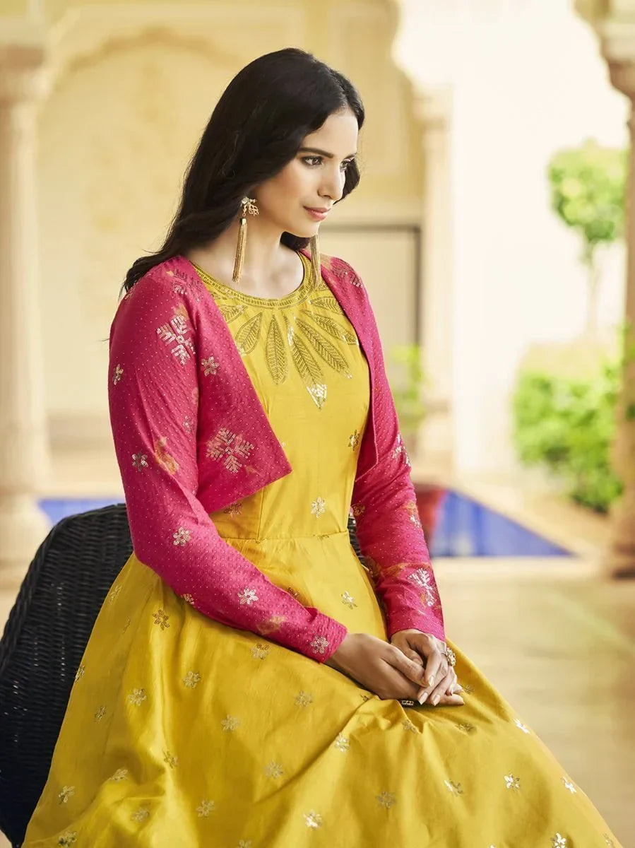 Woman in yellow embroidered ethnic gown with pink shrug, traditional Indian attire