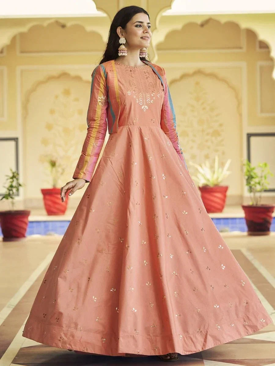 Woman in peach ethnic gown with gold embroidery and multicolor sleeves, indoor Indian setting