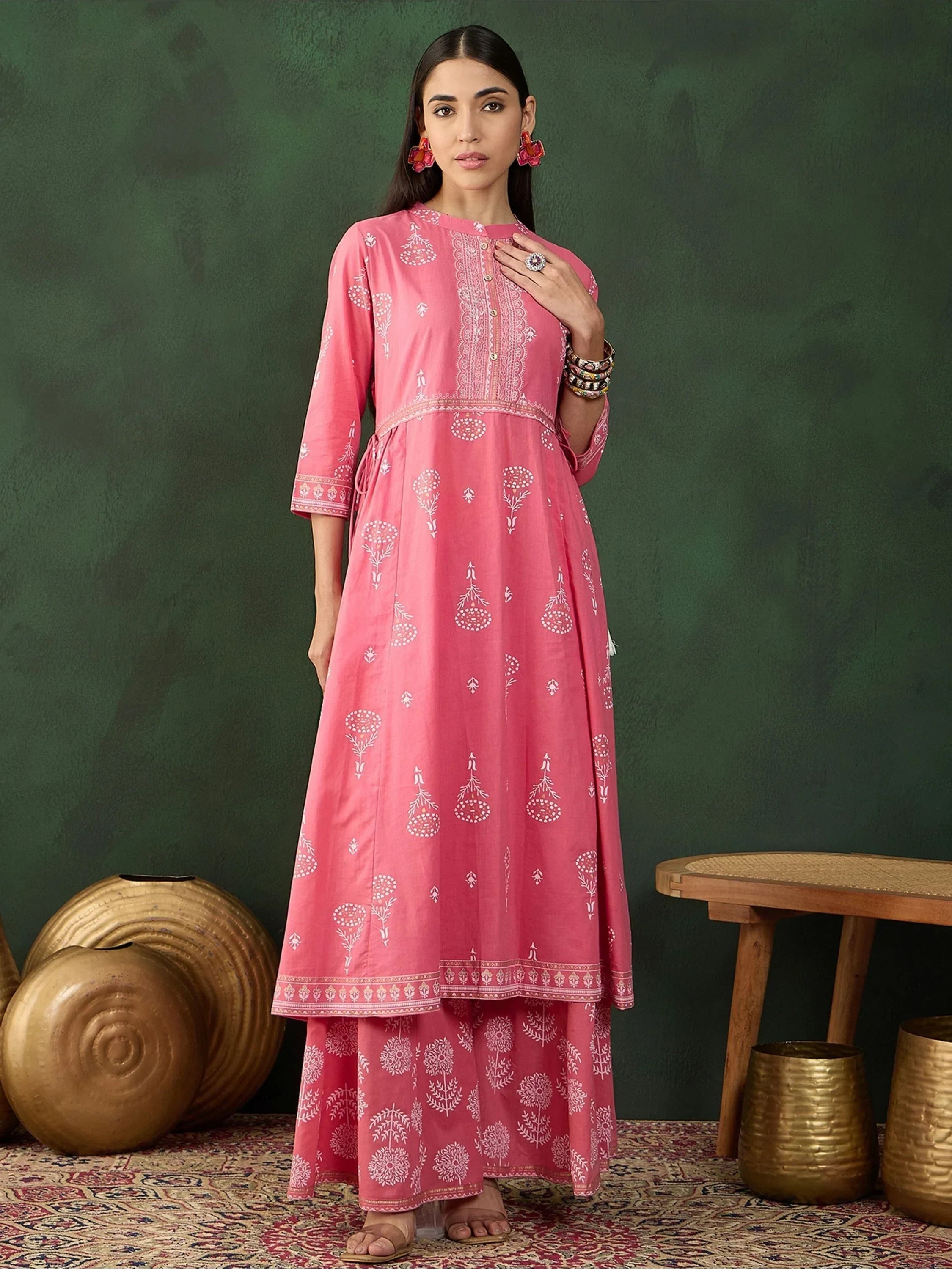 Woman wearing pink printed ethnic kurta and palazzo set with traditional jewelry