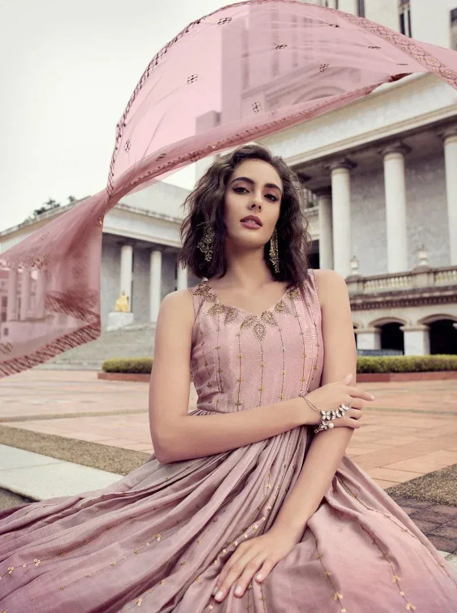 Woman in elegant mauve ethnic gown with gold embroidery, outdoor with dupatta flowing