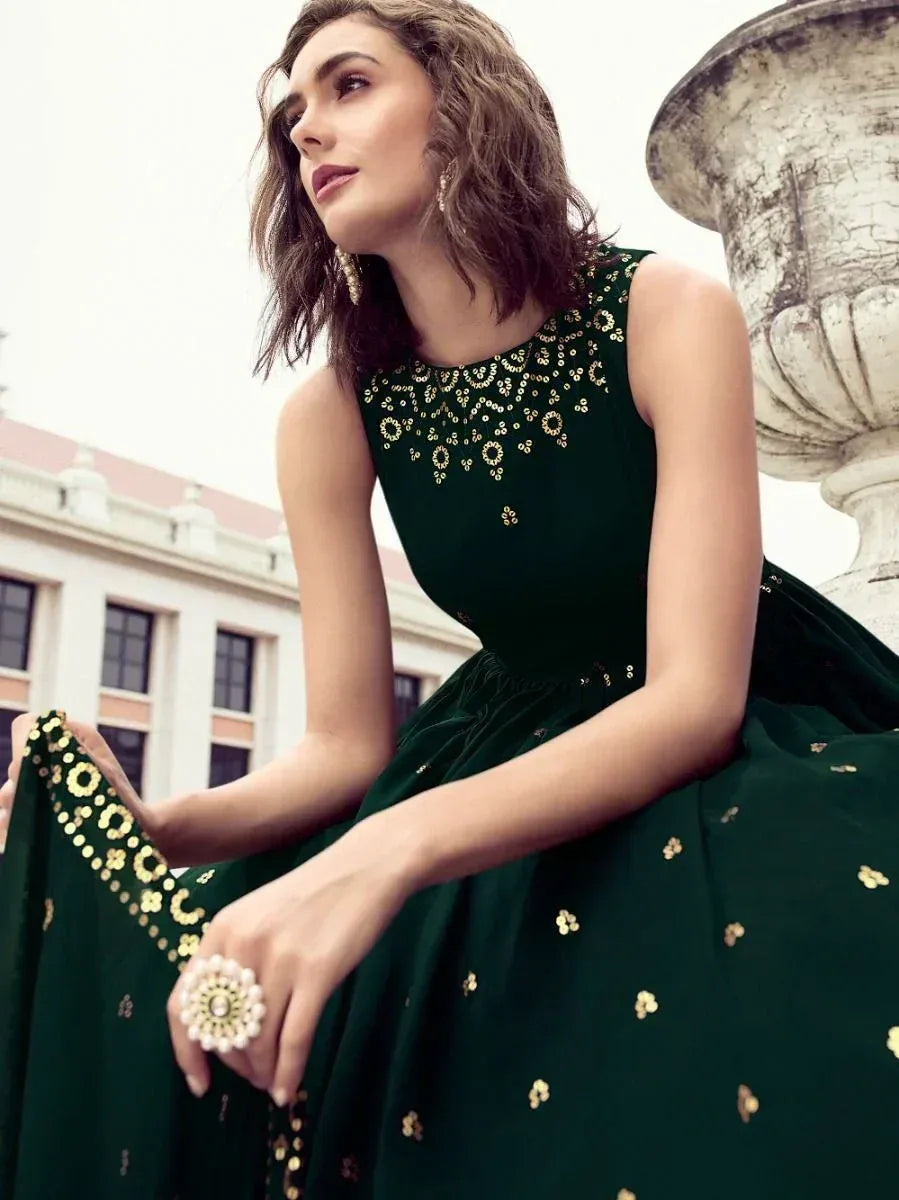 Woman in sleeveless dark green ethnic gown with gold embroidery, outdoor setting
