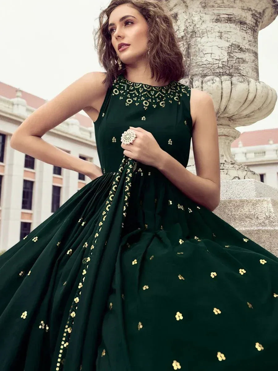 Woman wearing dark green embroidered ethnic gown with gold accents, outdoor setting