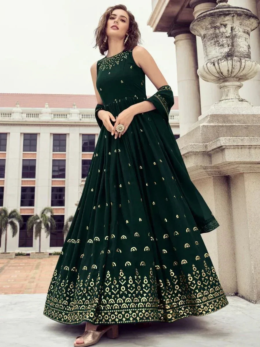 Woman in dark green embroidered ethnic gown with gold accents, posing outdoors