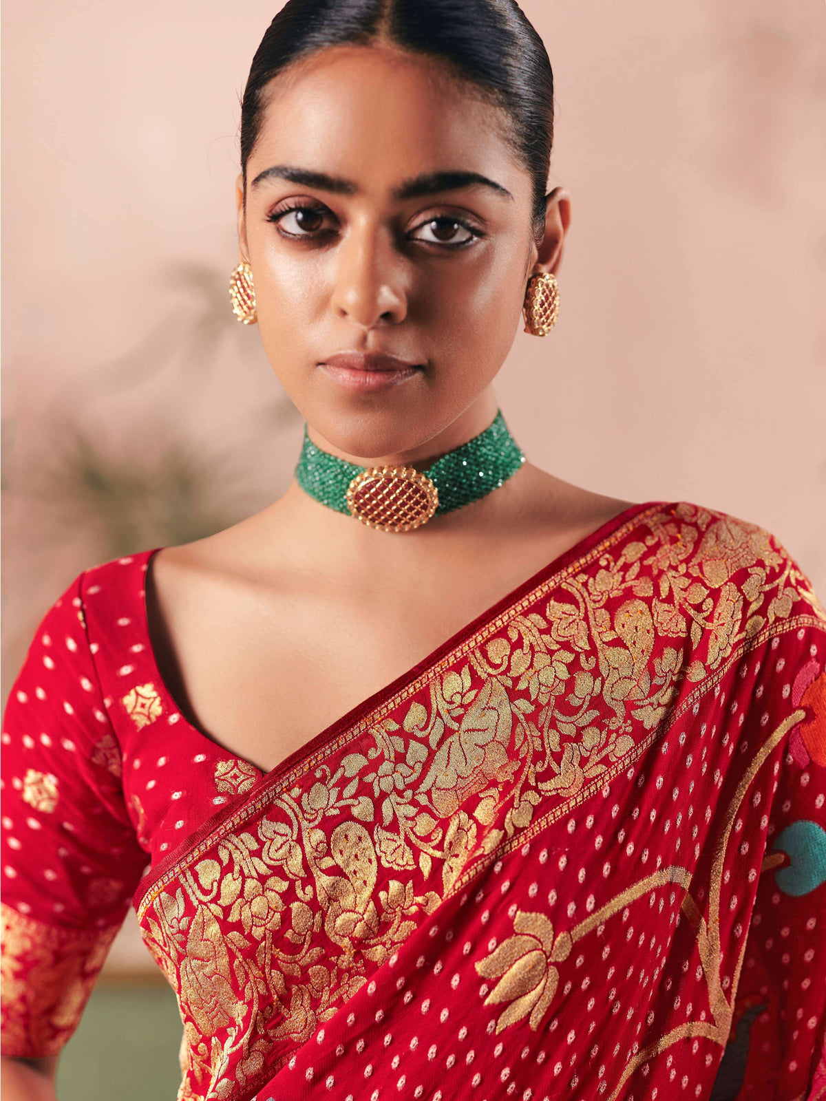 Red and gold embroidered saree with green choker necklace