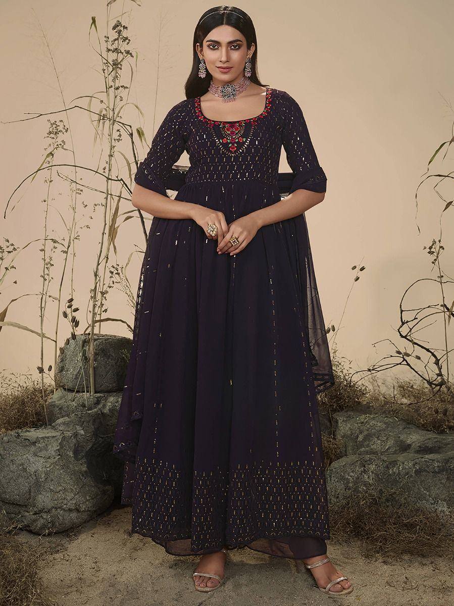 Woman in a navy blue embroidered ethnic gown with gold accents, standing outdoors
