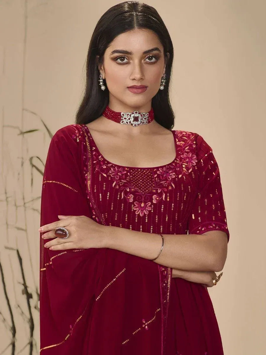 Woman wearing maroon embroidered ethnic gown with floral sequin work and jewelry