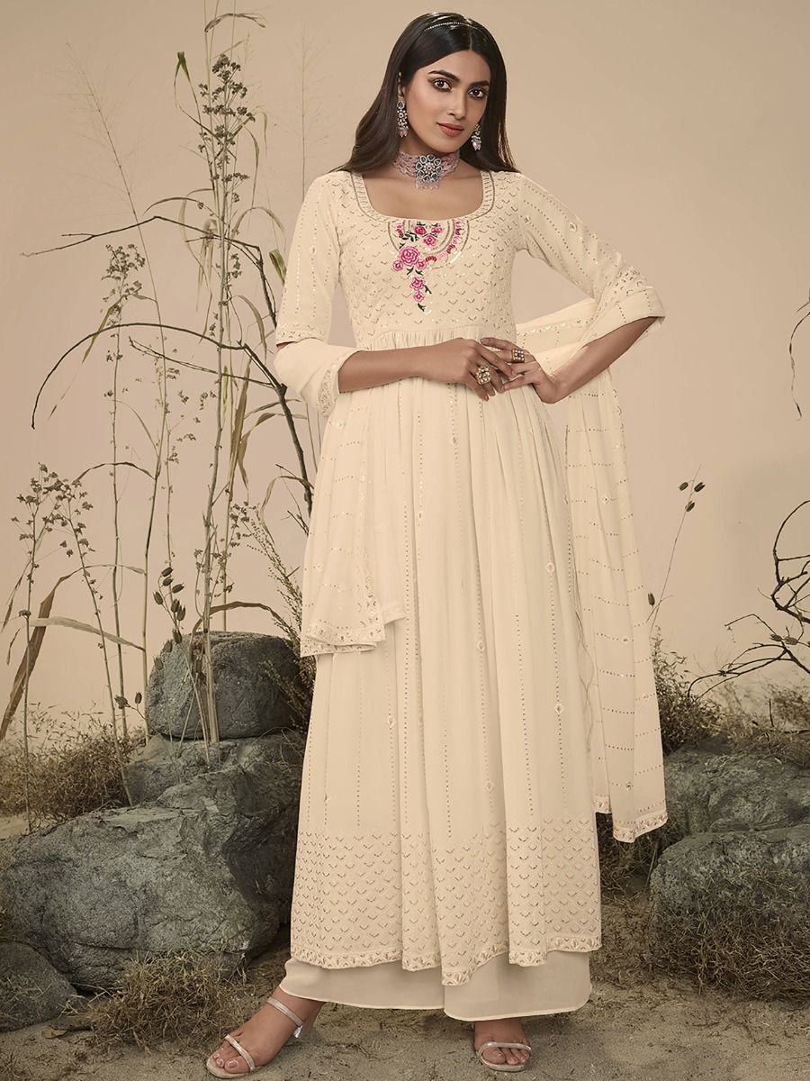 Woman in cream embroidered anarkali suit with floral neckline, standing outdoors