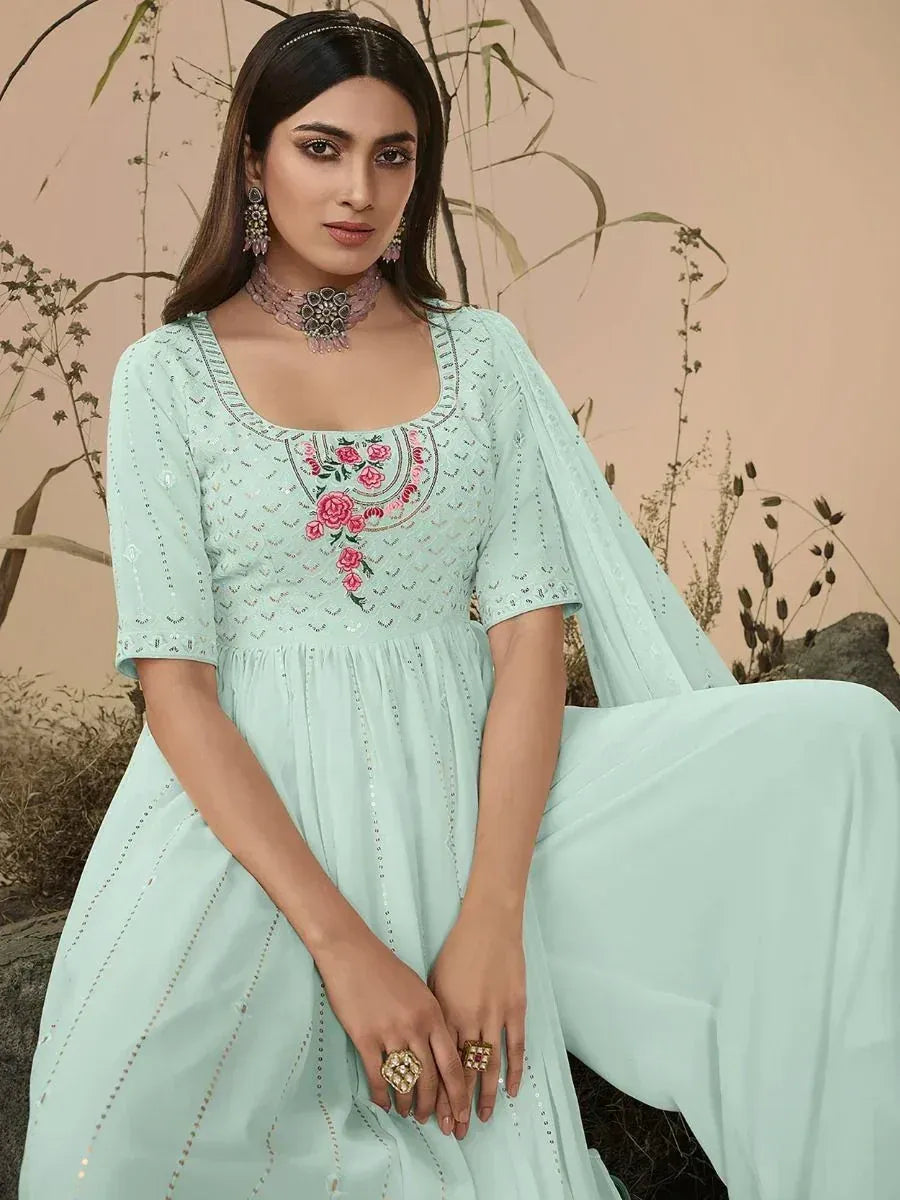 Woman wearing light blue embroidered ethnic gown with floral detailing and statement jewelry