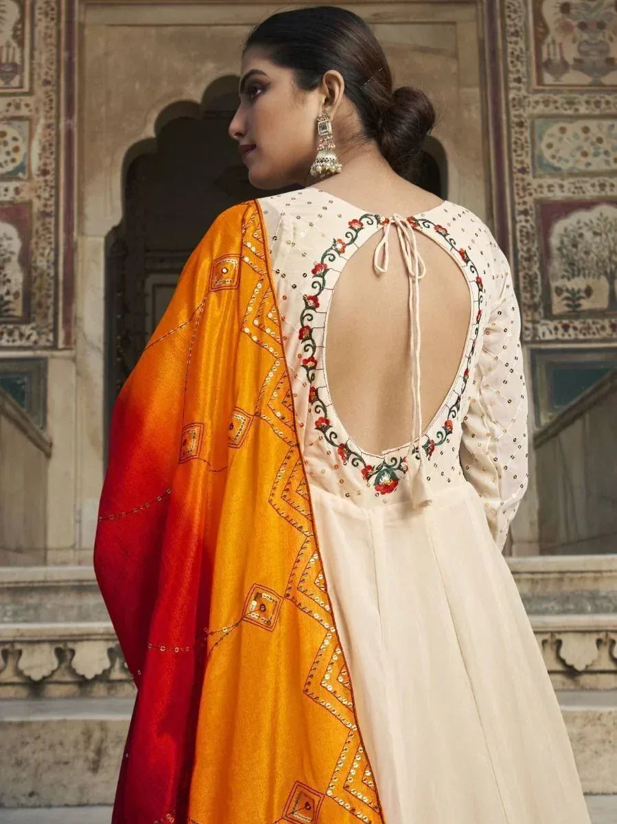 Elegant cream salwar kameez with floral back embroidery and orange-red dupatta, perfect for ethnic occasions.