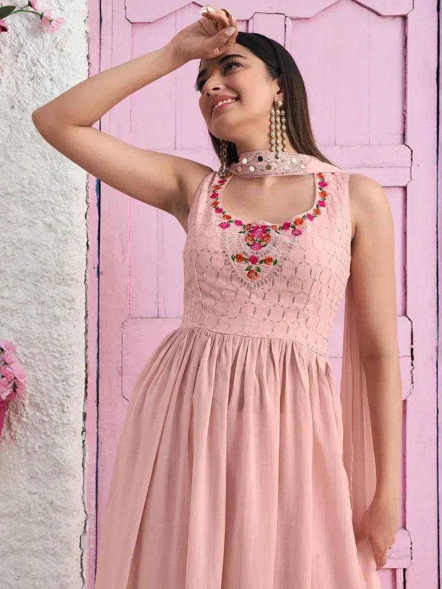 Woman wearing a pastel pink ethnic gown with floral embroidery and statement earrings