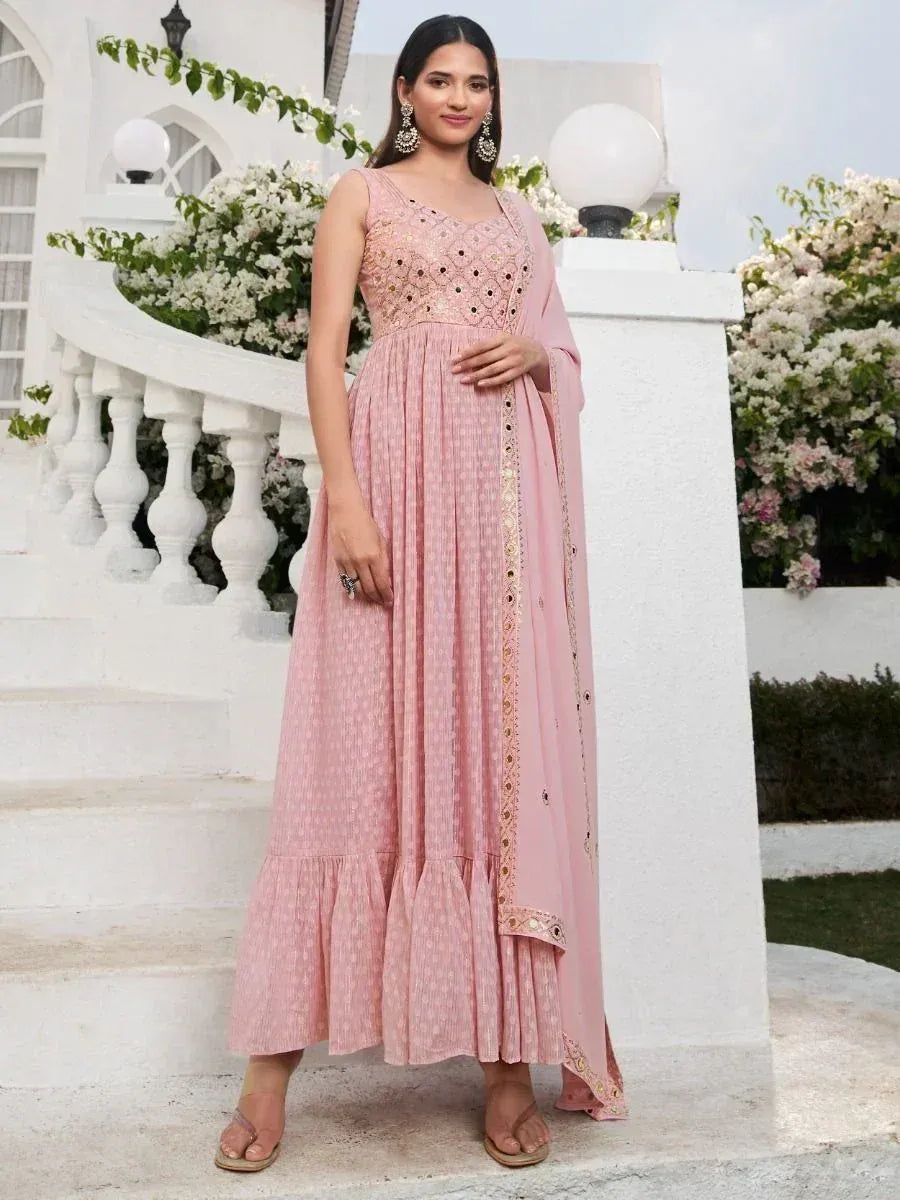 Woman in a sleeveless pink embroidered ethnic gown with dupatta, standing outdoors