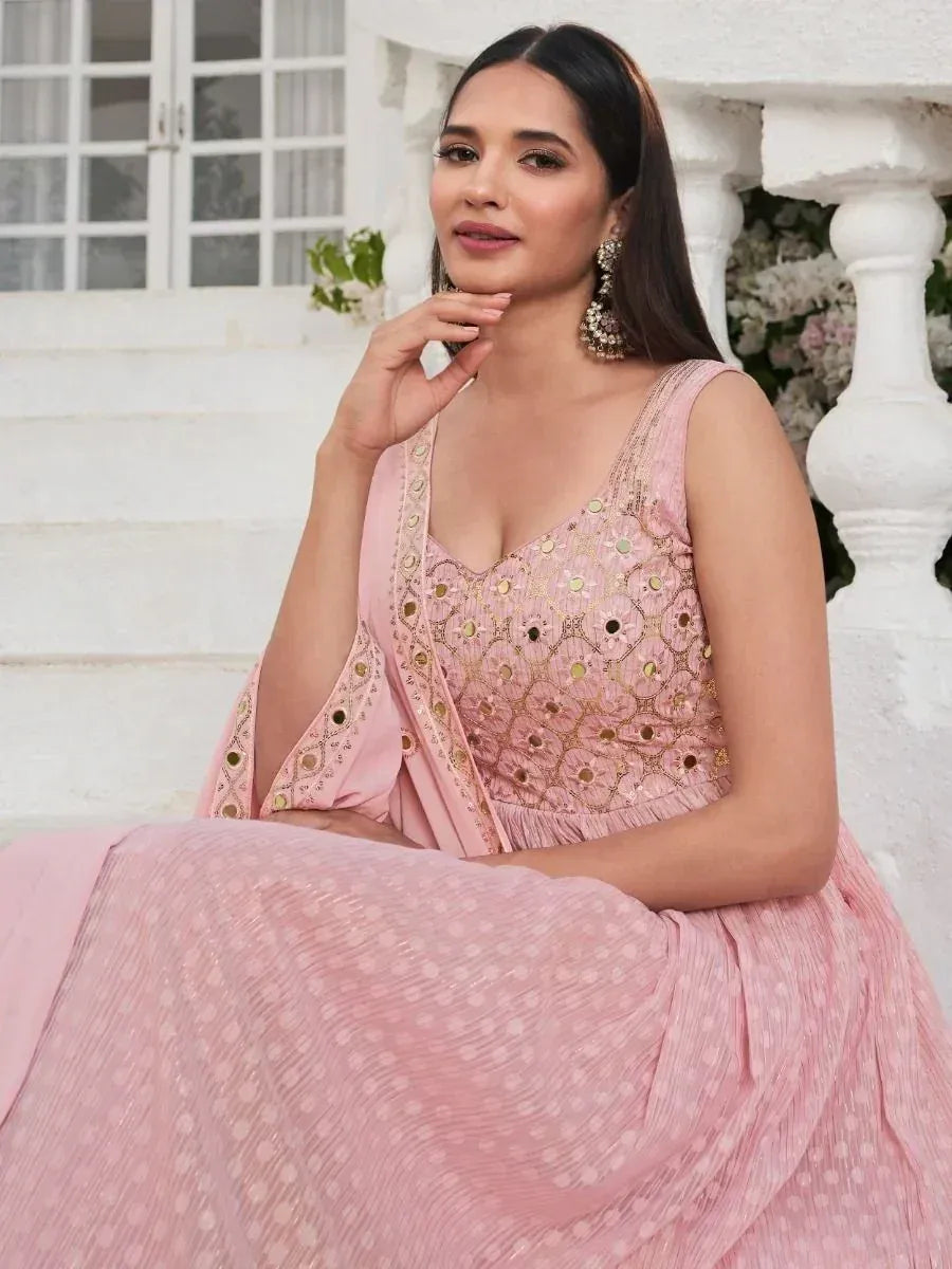 Woman in a pink embroidered lehenga choli with mirror work, seated outdoors