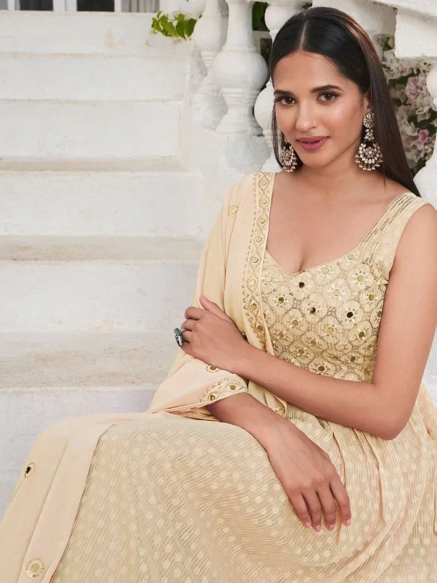 Woman in cream embroidered ethnic gown with dupatta, wearing statement earrings