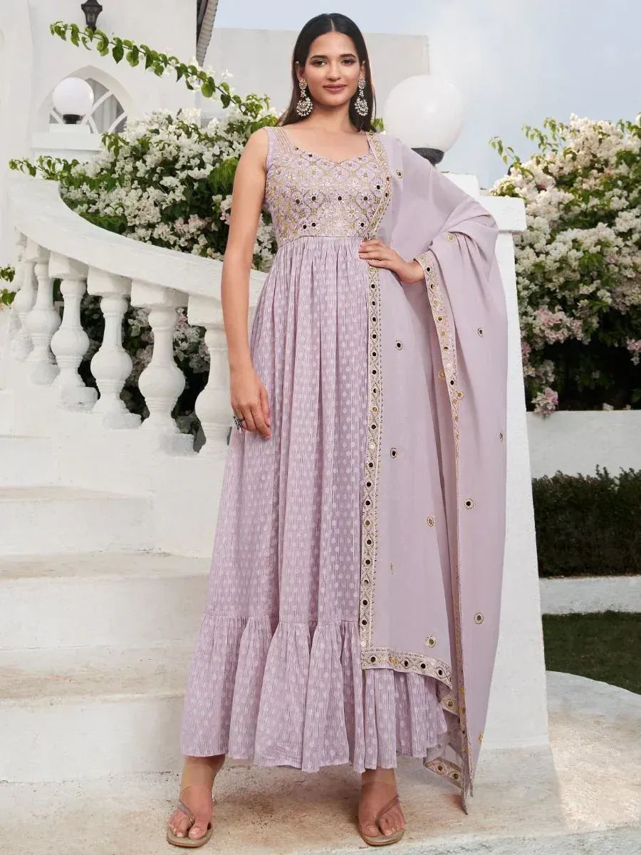 Woman wearing lavender ethnic gown with embroidery, matching dupatta, outdoor setting