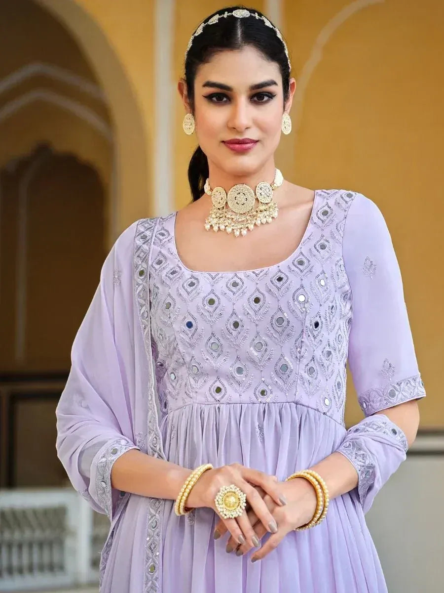 Woman in lavender embroidered ethnic gown with mirror work, traditional jewelry, and bangles