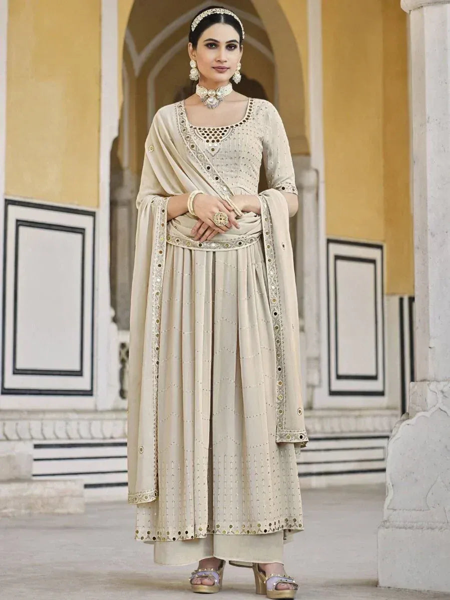 Woman in beige embroidered Indian salwar kameez with dupatta and traditional jewelry