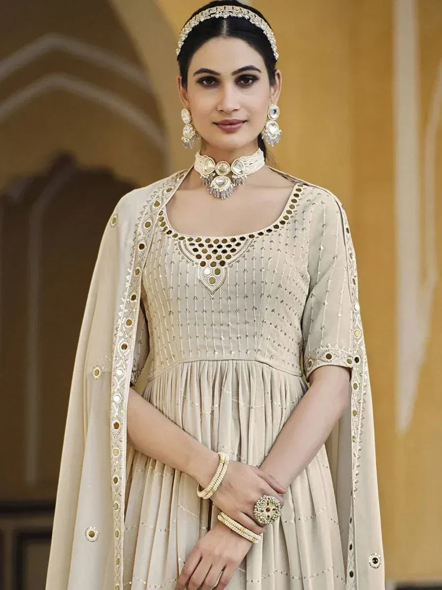 Woman in cream embroidered ethnic gown with matching dupatta and traditional jewelry