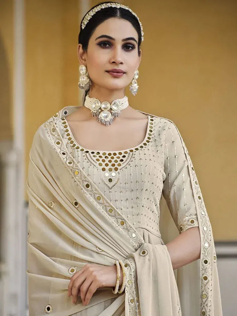 Woman wearing beige embroidered saree with mirror work and statement jewelry