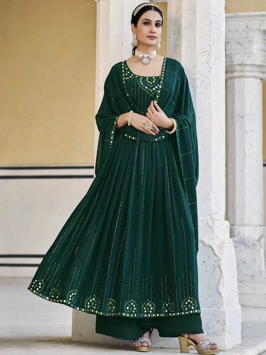 Woman in a dark green designer ethnic gown with mirror work, wearing traditional jewelry