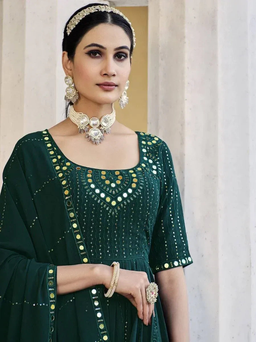 Woman in green embellished ethnic gown with mirror work, wearing traditional jewelry