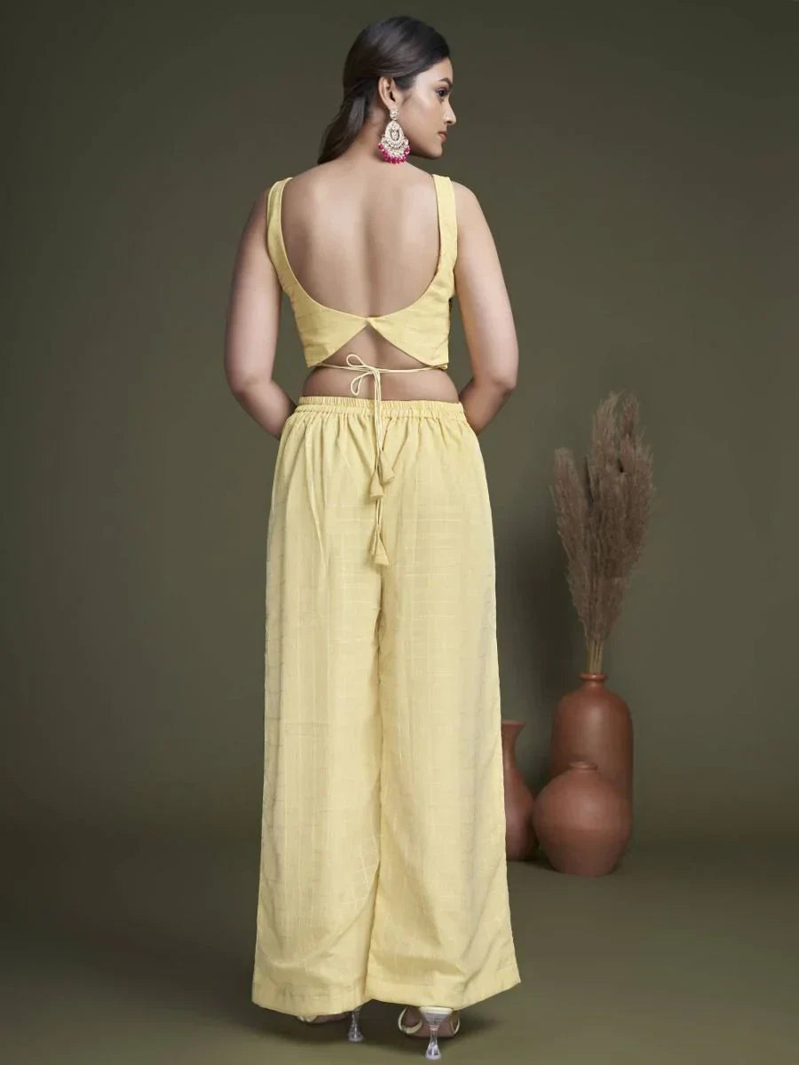 Woman in yellow ethnic crop top and palazzo pants set, back view, with statement earrings