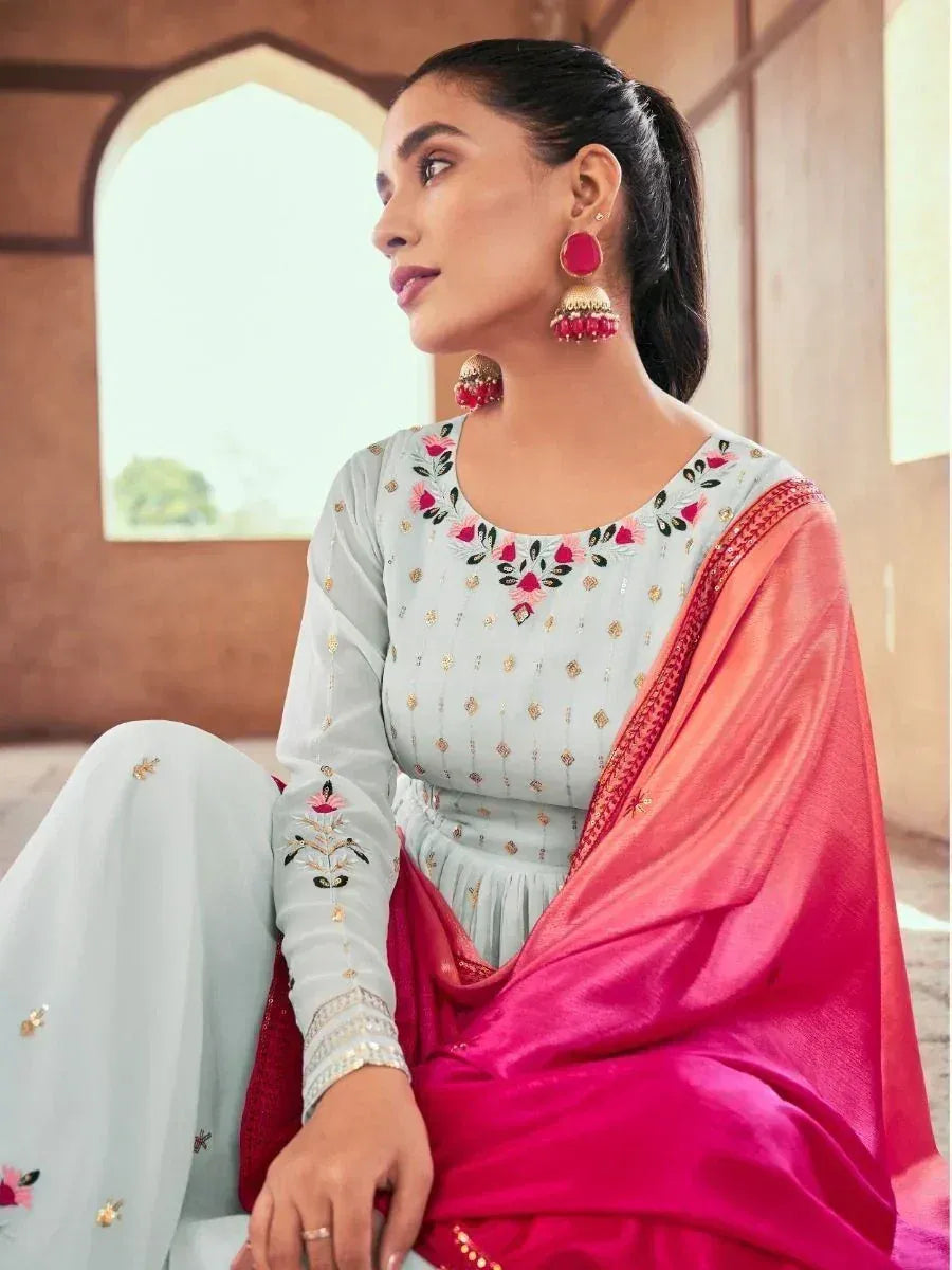 Woman in light blue embroidered salwar kameez with pink dupatta and jhumka earrings
