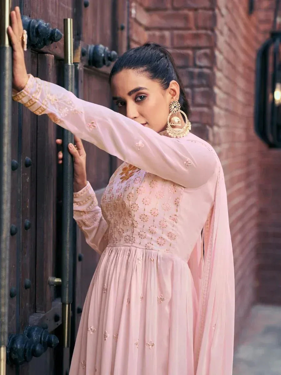Woman in pastel pink embroidered ethnic gown with dupatta and statement earrings