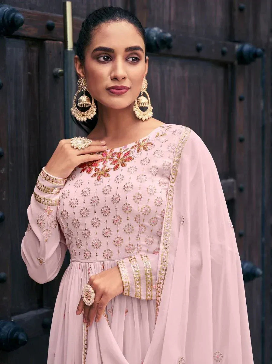Woman in pastel pink embroidered Indian salwar kameez with statement earrings and dupatta