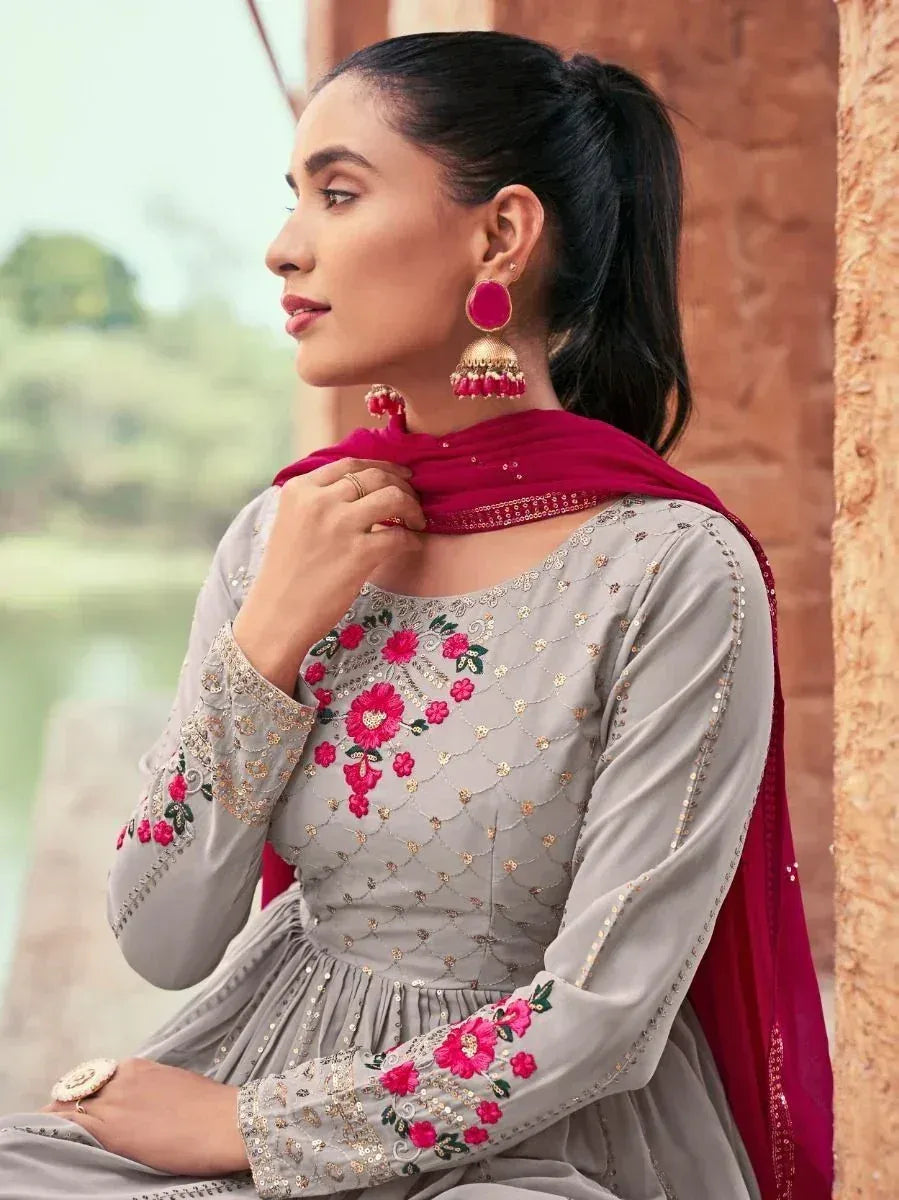 Woman in silver embroidered ethnic gown with pink floral details and matching dupatta