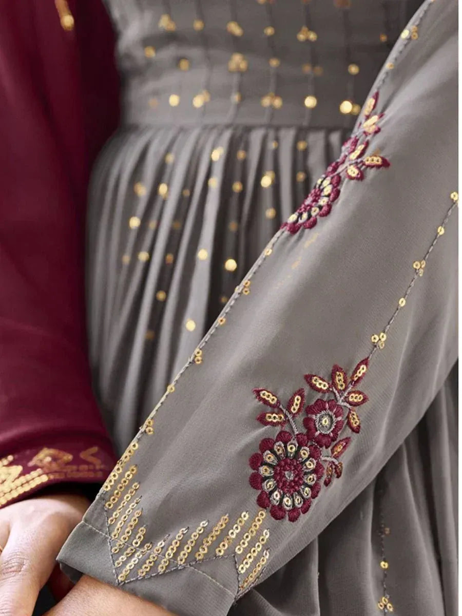 Close-up of grey ethnic gown sleeve with maroon floral embroidery and gold sequin details
