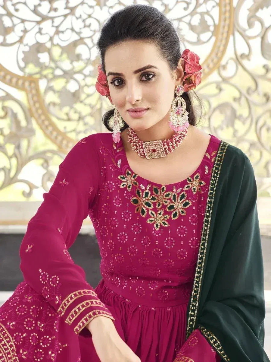 Woman in magenta embroidered Indian ethnic gown with green dupatta, floral jewelry and earrings