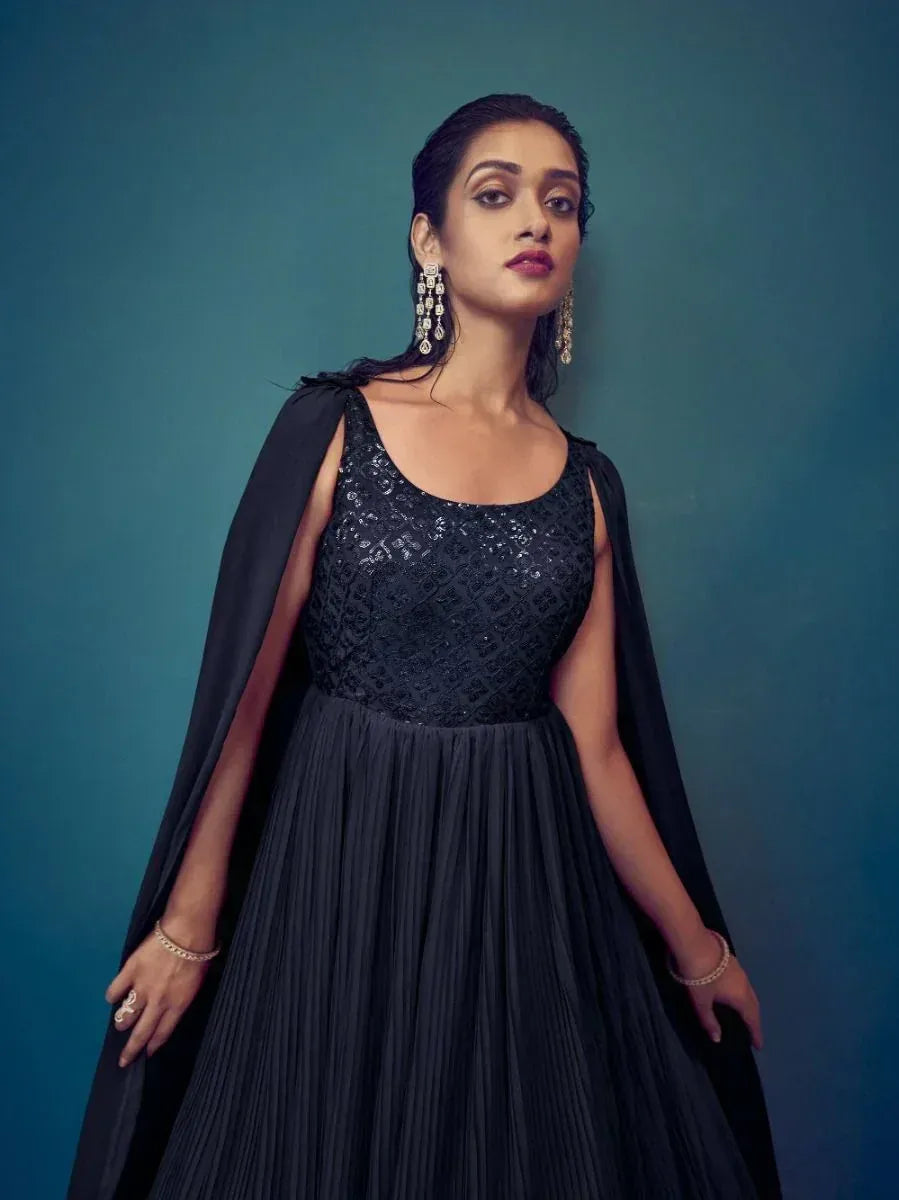 Woman in a sleeveless black ethnic gown with sequin bodice and statement earrings