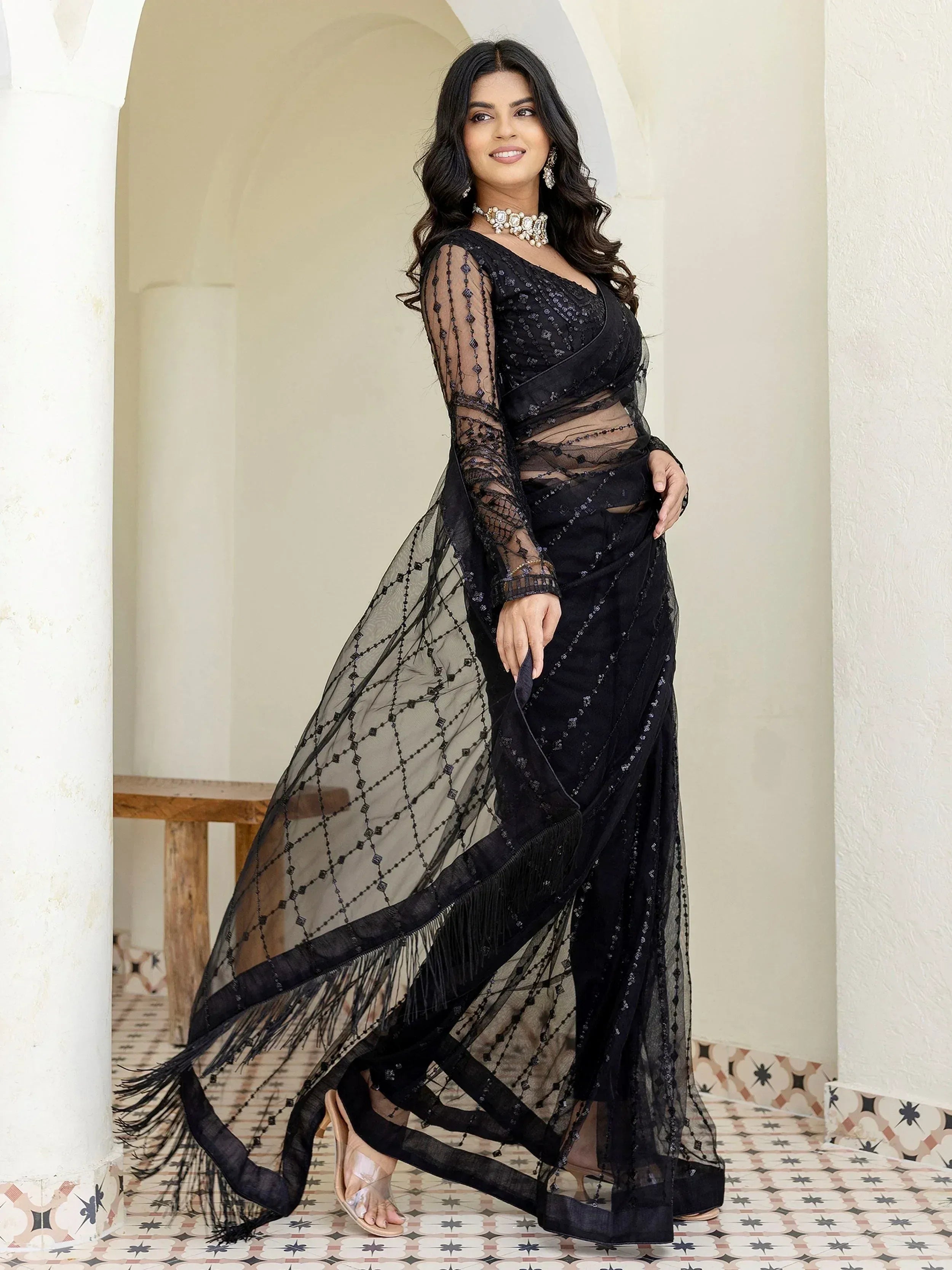 Black sheer saree with sequins and fringe, styled with statement jewelry for ethnic occasions