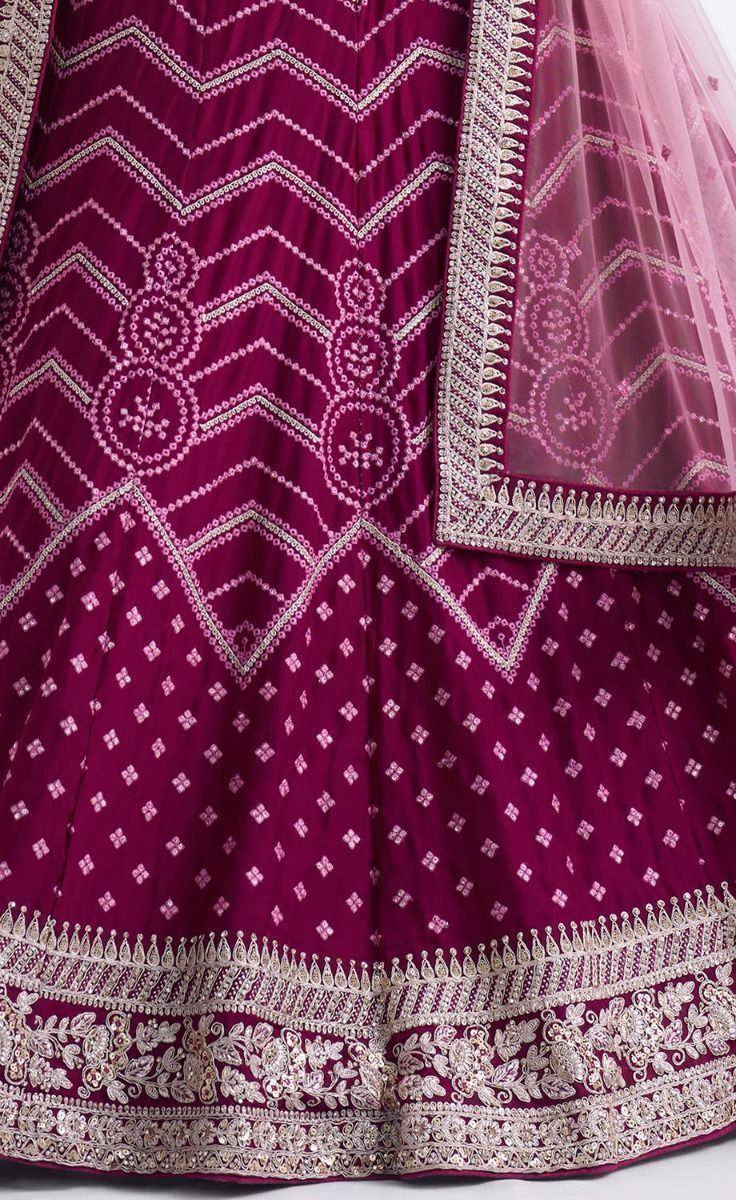 Magenta lehenga with intricate white embroidery and geometric patterns, paired with sheer dupatta